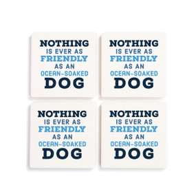 A set of four white ceramic coasters with the saying "Nothing is ever as friendly as an ocean-soaked dog".
