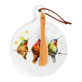 A round ceramic white mini serving board with a watercolor image of hummingbirds on a branch. The board has a small wood knife attached.