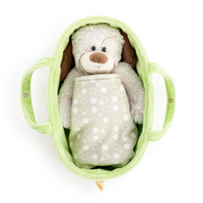 A cream and brown plush puppy inside a light green fabric carrier covered with a tan blanket.