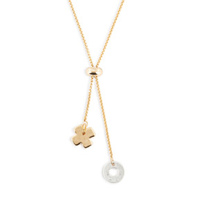 Detail view of the charms on an adjustable gold chain lariat necklace with a silver O and gold X at the ends.