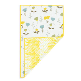 A rectangular double sided towel. One side is white with yellow spots and the other is white with illustrated flowers, displayed with the spotted corner turned back.