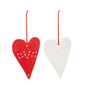 A set of two heart shaped ceramic ornaments, one red and one white. The ornaments have decorative markings and holes.