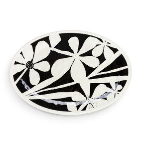 Top down view of a large white oval melamine platter with a black and white floral pattern on the top.