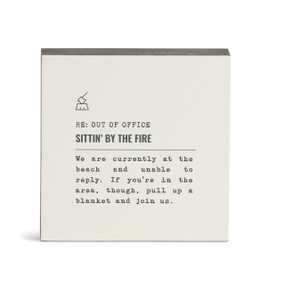 A white square wall art with the saying "RE: Out of Office Sittin' by the Fire" with a short write up about someone sitting by a fire on the beach.