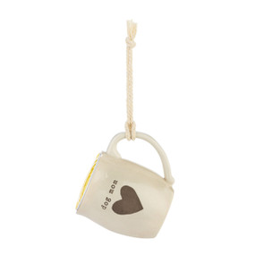 A cream ceramic mini mug that says "dog mom" with the image of a heart on the front, shown hanging with a coffee pod inside.