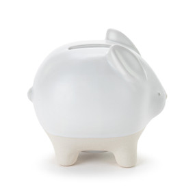 A white ceramic piggy bank with the face and ears of a bunny. The feet of the bank are cream and textured.
