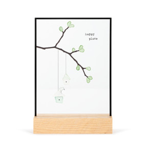 A large rectangular suncatcher in a light wood base. The image is a leafy branch with small birdhouses hanging from it made from small colored stones and has the saying "happy place".