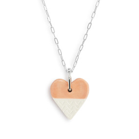 Detail view of the heart charm on an adjustable silver chain necklace with a heart shaped pink and white diffuser charm.