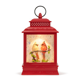 A red lit musical lantern with the image of a cardinal pair sitting on a branch in the snow.
