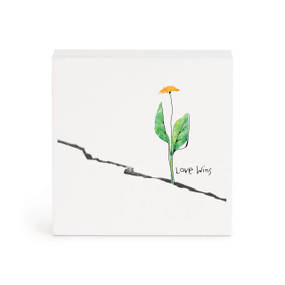 A small white box artwork of a dandelion growing out of a crack with the saying "Love wins".