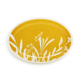 Top down view of a large mustard yellow oval melamine platter with a white leaf pattern on the top.