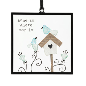 A small square suncatcher with a birdhouse and flowers made out of small colored stones and the saying "home is where mom is".