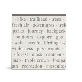 A white square wall art with words about hiking on it.