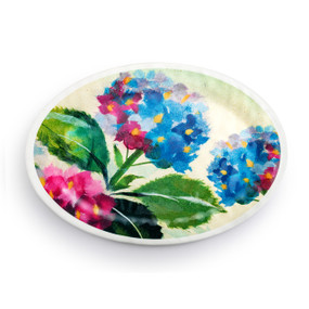 Top down view of a large white oval melamine platter with a pink and blue hydrangea flower image on top.