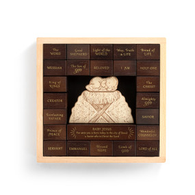A light wood box with dark wood pieces inside with different names for Jesus. There is a light wood manger and baby Jesus in the middle.
