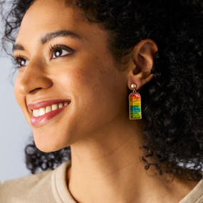 A woman wearing a pair of earrings with rows of color mimicking a horizon.