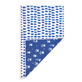A rectangular double sided towel. One side is white with blue spots and the other is blue with white illustrated flowers, displayed with the blue corner turned back.
