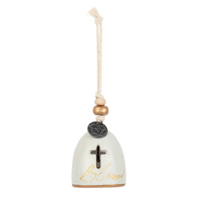 A mini cream bell with a cross shaped cutout and the word "Blessed" on the front. There are beads and a metal token at the top of the bell.