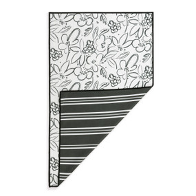 A rectangular double sided towel. One side is white with line drawn flowers and the other is black with white stripes, displayed with the black corner turned back.