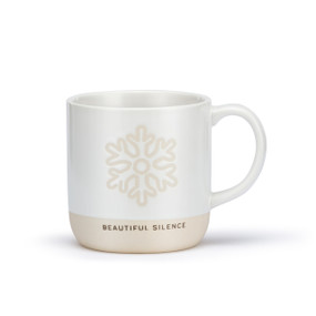 A white ceramic mug with a snowflake shaped cream meditation path on the mug and a cream textured base that says "Beautiful Silence".