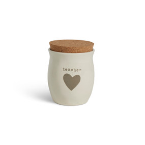 A cream ceramic candle with a gray heart and the word "teacher". The candle has a cork lid.