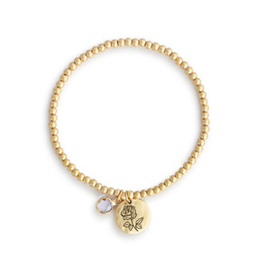 A gold beaded bracelet with a rose flower round charm and pearl colored stone.