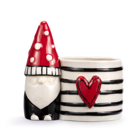 A mini white ceramic planter with a red and black gnome figure attached to the side. The planter has black stripes and a raised red heart on the front.