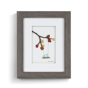 A gray wood framed image of two birds on a swing hanging from fall tree branches made of pebbles.