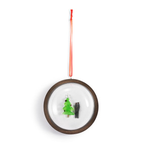 A hanging glass dome ornament on a wood base. The inside has a pebble image of a couple by a Christmas tree.