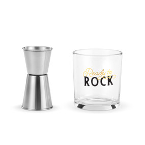 A clear rocks glass with the saying "Ready to Rock" next to a silver metal jigger.