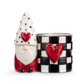 A mini white ceramic planter with a red and white gnome figure attached to the side. The planter has a black and white check pattern and a raised red heart on the front.