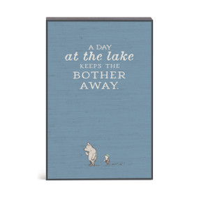 A dark blue wall art with an illustration of Pooh and Piglet and the saying "A day at the lake keeps the bother away."