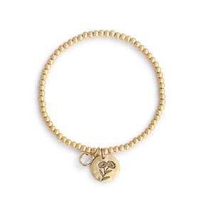A gold beaded bracelet with a daisy flower round charm and diamond colored stone.