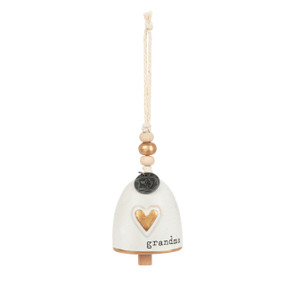 A mini cream bell with a gold heart on the front and the word "grandma". There are beads and a metal token at the top of the bell.
