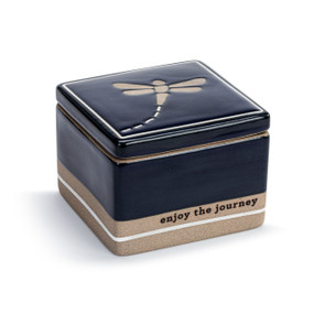 A dark blue and brown square ceramic keepsake box with a lid. The lid has a dragonfly and the box says "enjoy the journey" near the bottom, displayed angled to the right.