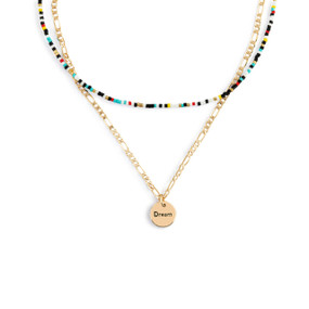A layered necklace made up of a gold chain with a round gold charm that says "Dream" and a layer of multicolored small beads.