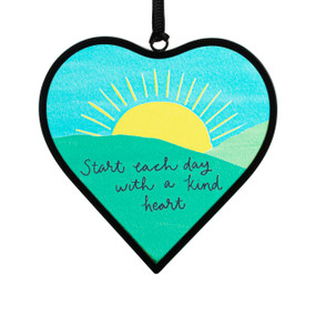 A small blue and green heart shaped sun catcher with a sunrise illustration and the saying "Start each day with a kind heart".