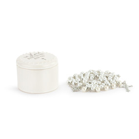 A round white ceramic trinket box next to a silver and white bead rosary.