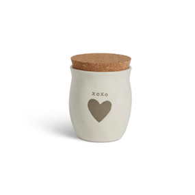A cream ceramic candle with a gray heart and the word "xoxo". The candle has a cork lid.