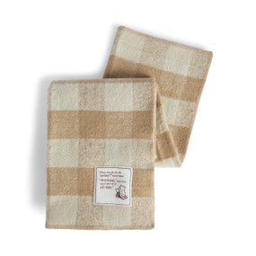 A tan and brown plaid blanket with a fabric patch of Pooh and Piglet that says "What should we do today?" asked Piglet. "Nothing," said Pooh. "And Let's do it all day."