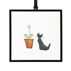 A small square suncatcher with a cat next to a plant made out of small colored stones.
