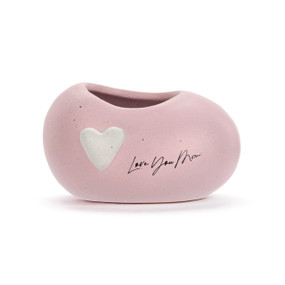A mini pink ceramic planter. It has a white heart and the saying "Love You Mom" on the front.