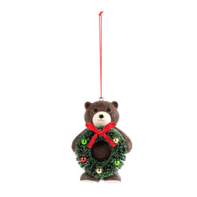 A small brown teddy bear ornament holding a green decorated wreath.
