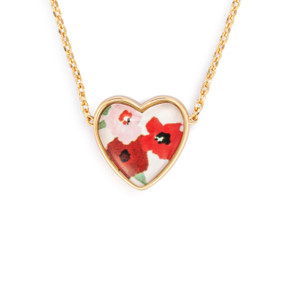 Detail view of the charm on an adjustable gold chain necklace with a heart shaped charm of red and pink flowers.