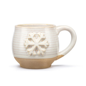 A cream ceramic mug with a tan textured base and cream interior. The mug has a raised snowflake on the front.