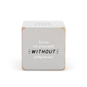 A large gray wood dice with an inspirational saying on each side in white and black print.