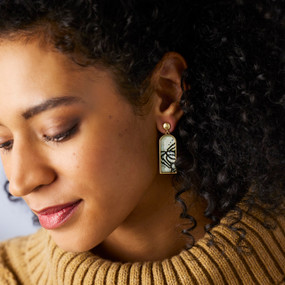 A woman wearing a pair of earrings with a vertical rectangle of black lines on white.