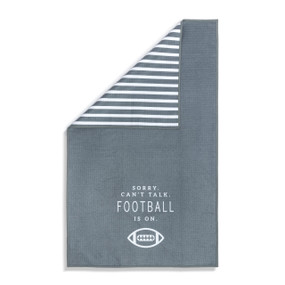 A gray and white double sided towel that has the saying "Sorry. Can't Talk. Football is on.". The towel is turned over at a corner showing the gray and white striped back.