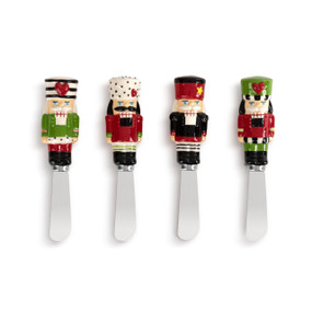 A set of four different spreaders. Each has a different red, white and green ceramic nutcracker on the handle.