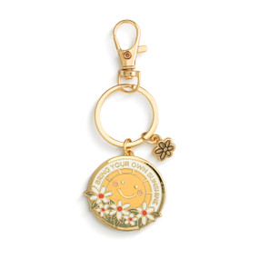 A gold keychain with two charms. One is a small gold flower and the other is a circle with the sun and flowers and has the saying "Bring Your Own Sunshine".